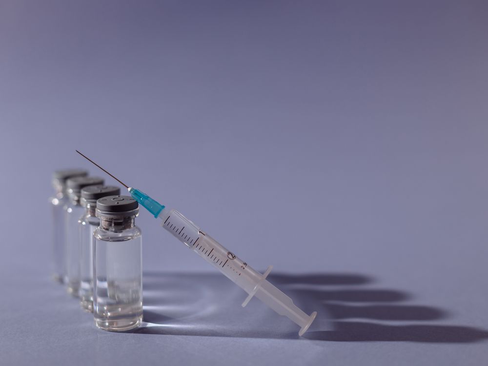 Syringe resting beside clinical vials